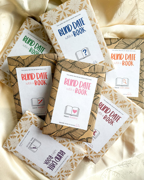 A collection of “Blind Date with a Book” wrapped books displayed on a white shelf, featuring different genres including romance, thriller, fantasy, cosy crime, and historical fiction, wrapped in patterned paper with minimalist genre labels and surprise book packaging.
