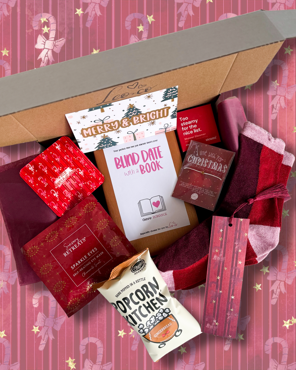 Christmas Blind Date With a Book gift box by Leo + Co, featuring a mystery book, cosy socks, shower steamer, Christmas wish bracelet, festive coaster, bookmark, self-heating eye mask and vegan gingerbread popcorn.