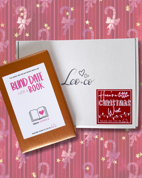 Christmas Blind Date With a Book gift box by Leo + Co, featuring a mystery book, cosy socks, shower steamer, Christmas wish bracelet, festive coaster, bookmark, self-heating eye mask and vegan gingerbread popcorn.